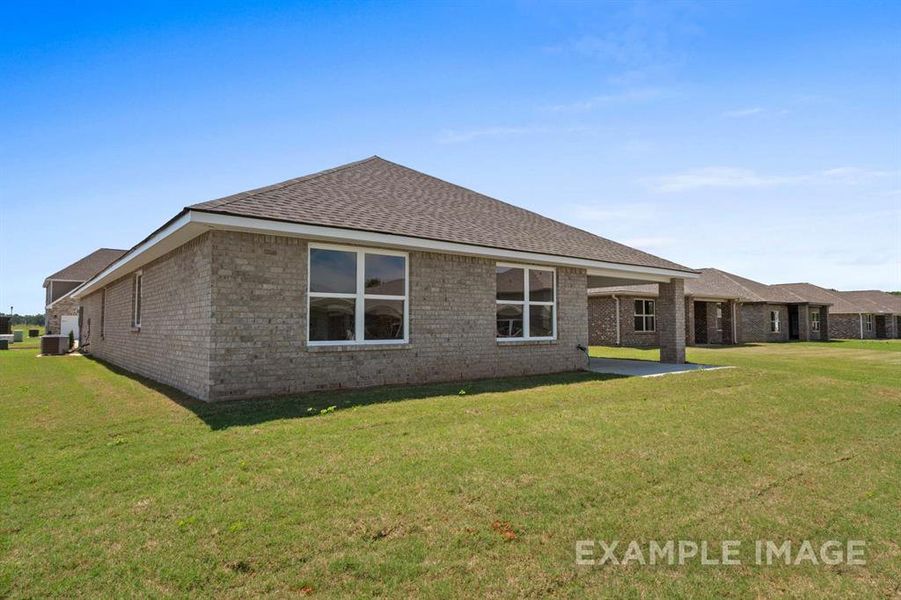 Back of property with a lawn, a patio, and central AC unit