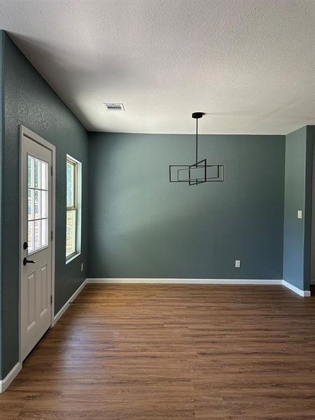 Unfurnished dining area featuring dark hardwood / wood-style floors and a textured ceiling