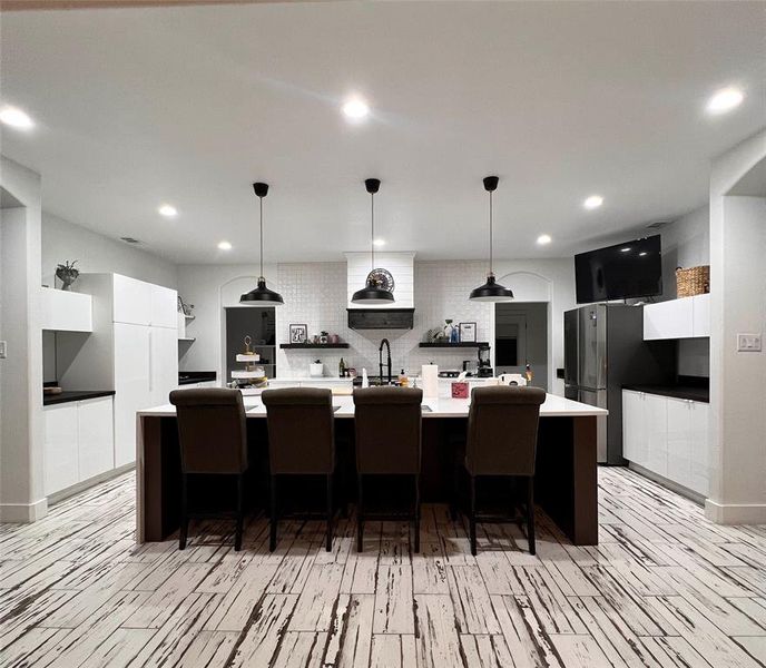 Kitchen featuring white cabinets, tasteful backsplash, and a spacious island