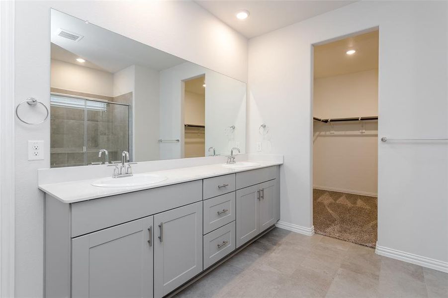 Primary bathroom featuring vanity, tile patterned flooring, and a shower with door