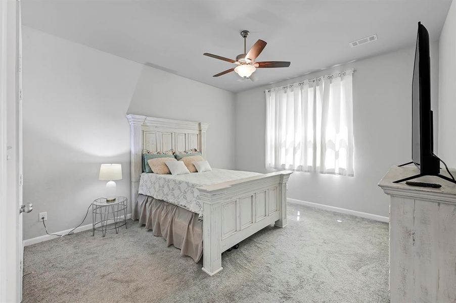 Discover serene comfort in this tranquil, well-lit primary bedroom featuring plush carpeting creating the perfect retreat for relaxation and rest.