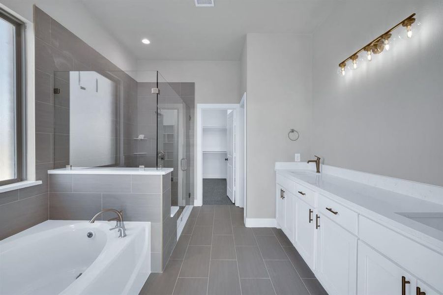 Bathroom with a wealth of natural light, shower with separate bathtub, tile patterned flooring, and dual bowl vanity