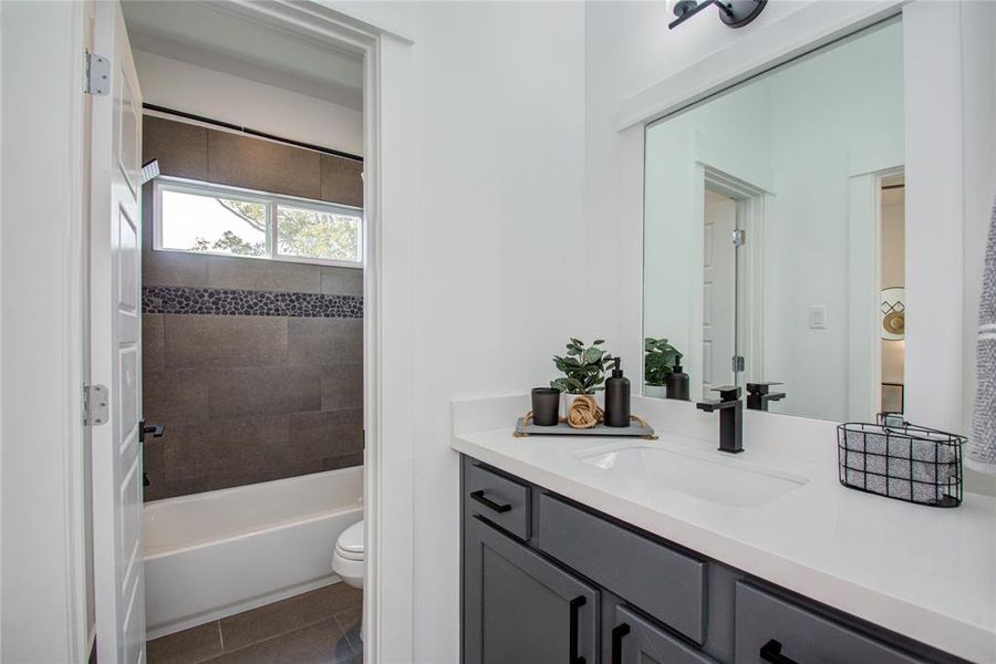 J&J bathroom, with access to the 2 secondary bedrooms, features Quartz countertops and soft close drawers. Model home photos - FINISHES AND LAYOUT MAY VARY!