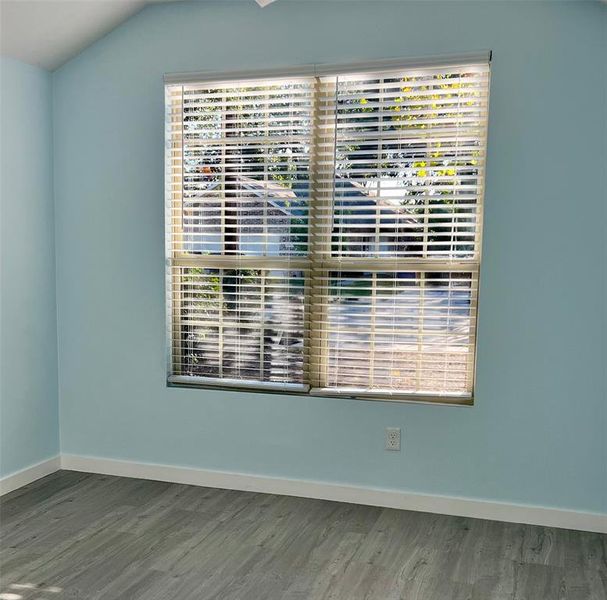 Unfurnished room with hardwood / wood-style flooring and vaulted ceiling