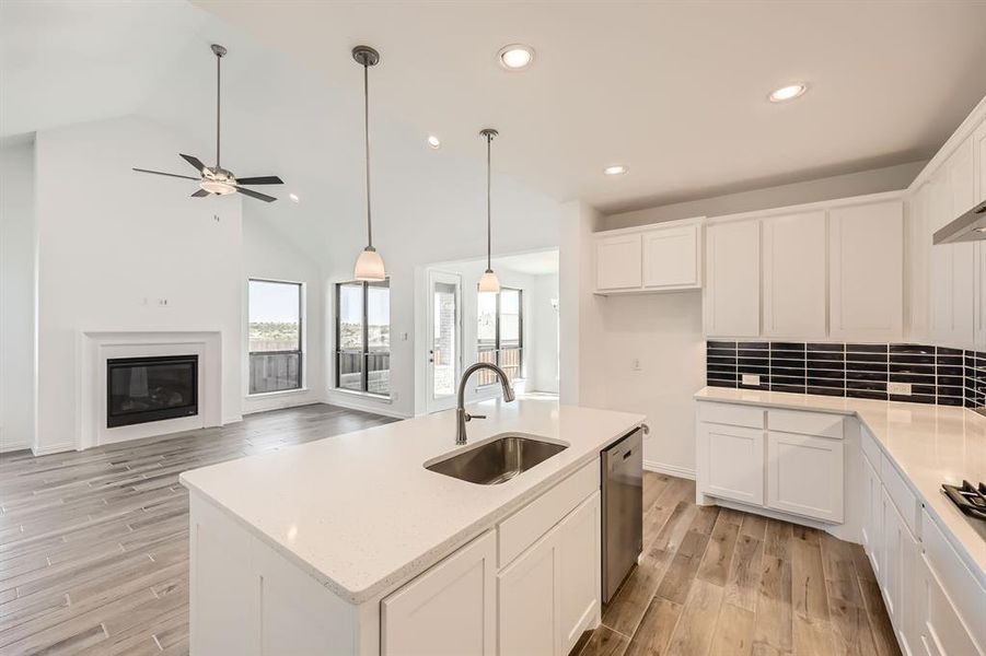 Kitchen with sink, light wood-type flooring, a center island with sink, and white cabinets