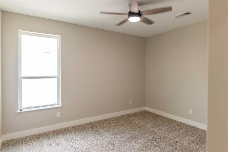 Carpeted empty room featuring a healthy amount of sunlight and ceiling fan