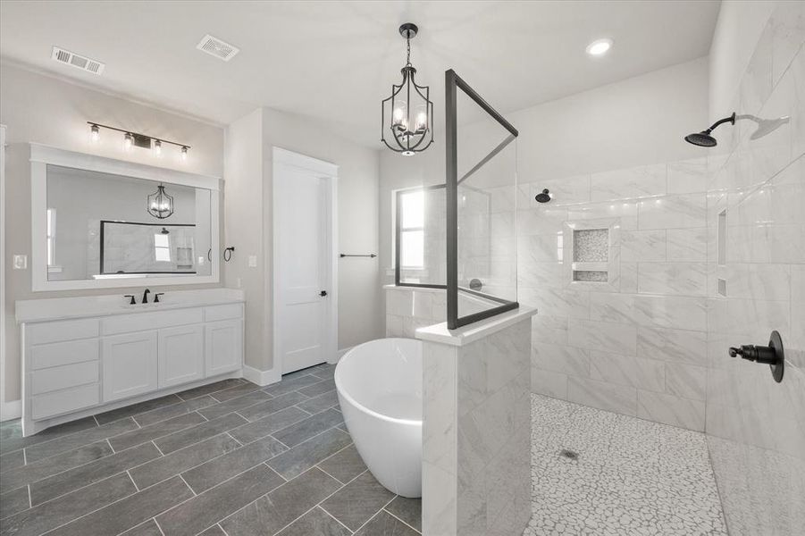 Bathroom featuring vanity, shower with separate bathtub, and an inviting chandelier