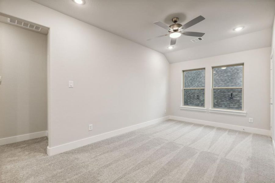 Carpeted spare room with lofted ceiling and ceiling fan