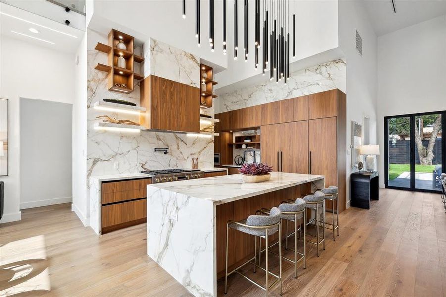 Chef's kitchen featuring large porcelain island with mitred waterfall edge and GE Monogram appliances.