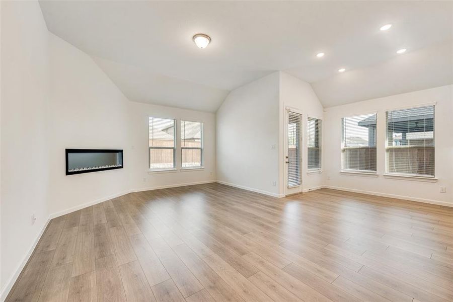 Unfurnished living room with lofted ceiling, plenty of natural light, and light hardwood / wood-style flooring