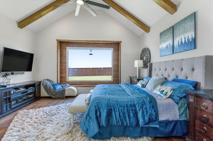 Bedroom with high vaulted ceiling, beam ceiling, ceiling fan, and hardwood / wood-style flooring