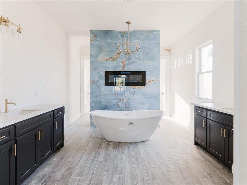 Bathroom with wood-type flooring, vanity, a bathing tub, and an inviting chandelier