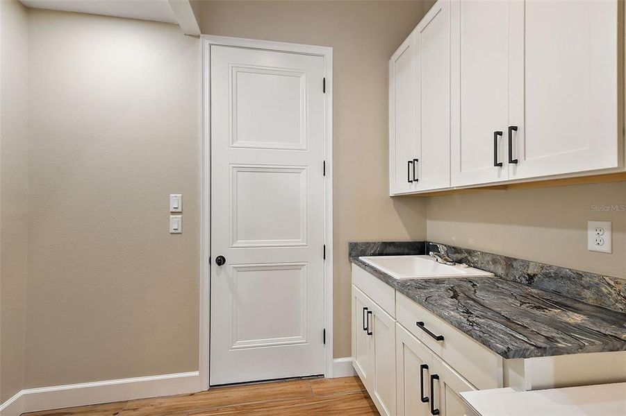 Dedicated laundry room with sink, Granite topped counter and cabinetry
