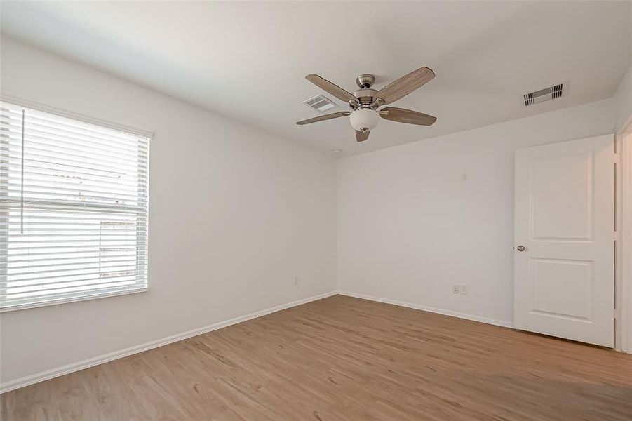 The primary bedroom features a large window that brings in natural light, complemented by a ceiling fan for added comfort and a refreshing breeze.