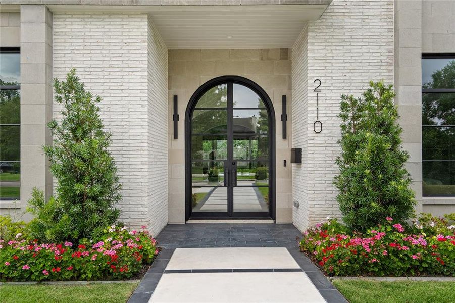 Exquisite slate tile steps are seamlessly complemented by low-profile handmade, lime-washed brick which exudes a sophisticated transitional charm. This elegant design is further enhanced by meticulously crafted limestone accents, adding a touch of timeless beauty to this spectacular front entrance.