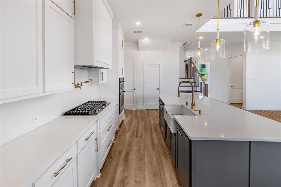 Kitchen featuring light stone countertops, decorative light fixtures, and white cabinets