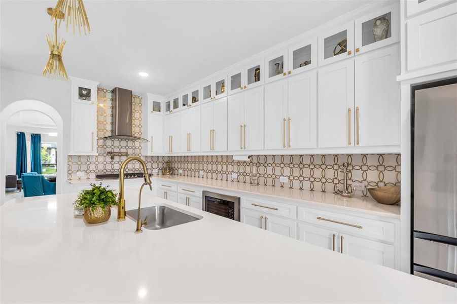 Kitchen featuring sink, wine cooler, backsplash, and wall chimney exhaust hood