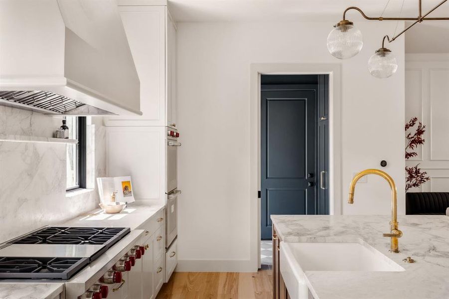 Apron farmhouse sink is adorned with burnished brass faucet.