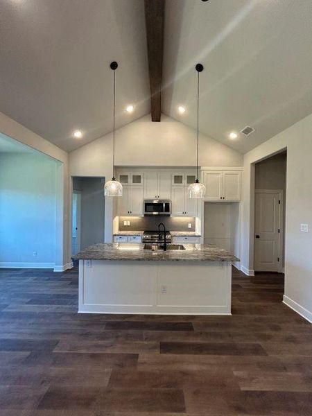 Kitchen featuring appliances with stainless steel finishes, stone countertops, and dark wood-type flooring