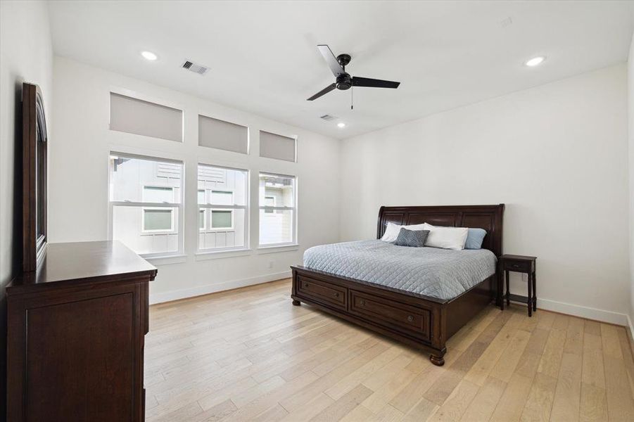 Large primary bedroom has tall ceilings, ceiling fan, and large enough for a sitting area.