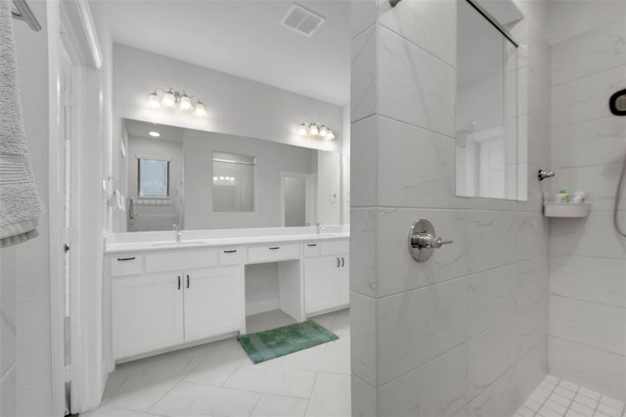 Bathroom with tiled shower and vanity