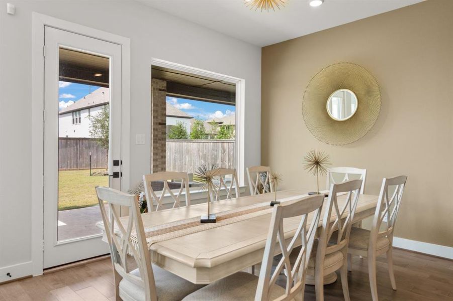 The breakfast area features a large window, hardwood flooring, and a convenient backdoor, providing a bright and inviting space for meals with easy outdoor access.