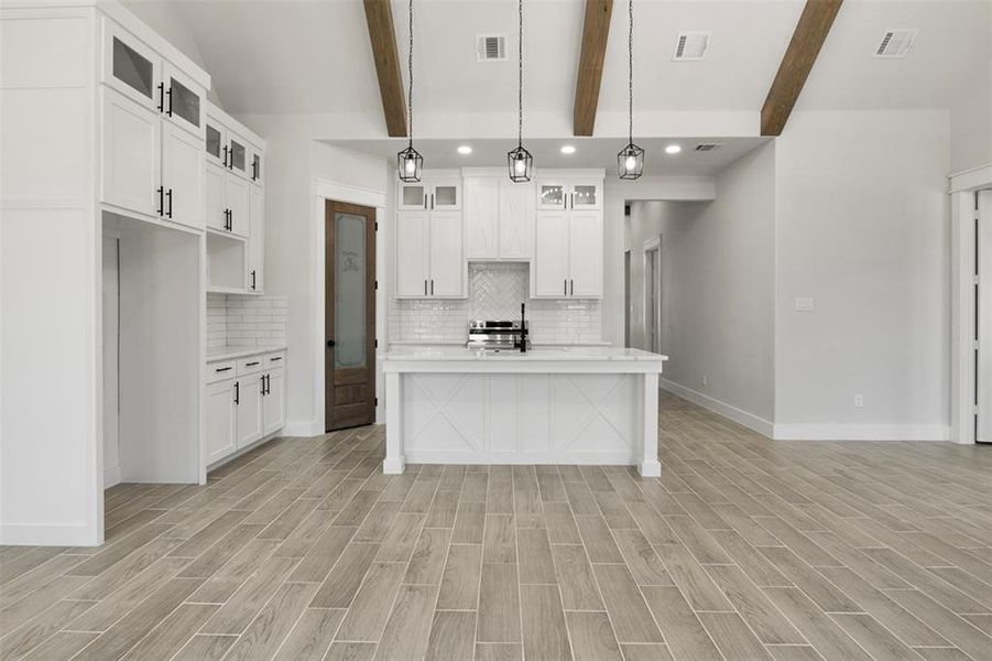 Kitchen featuring white cabinets, light hardwood / wood-style floors, hanging light fixtures, and beam ceiling