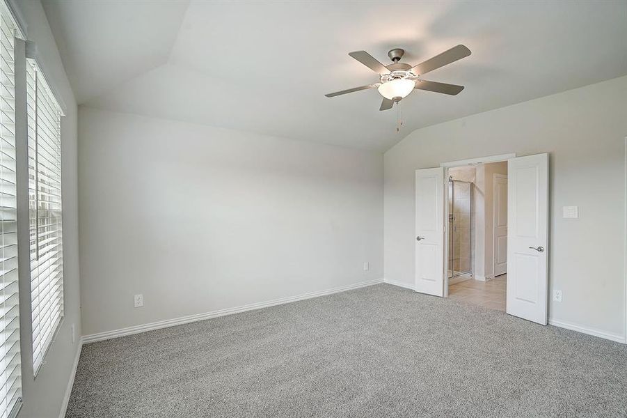 Carpeted bedroom with lofted ceiling and ceiling fan