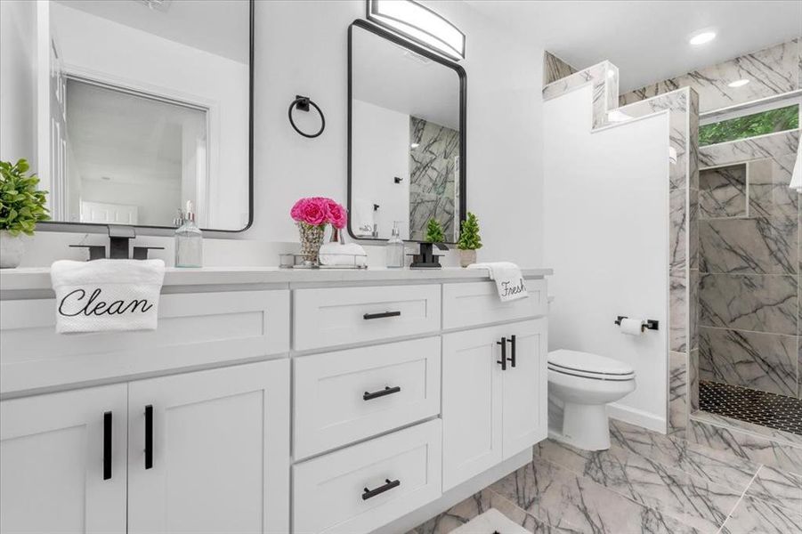 Bathroom with tile floors, tiled shower, toilet, and vanity