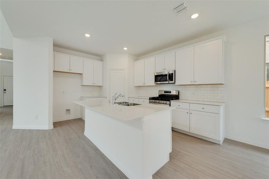 Kitchen with white cabinetry, a kitchen island with sink, sink, and stainless steel appliances