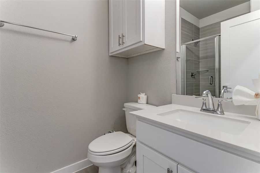 Bathroom with a shower with door, vanity, and toilet