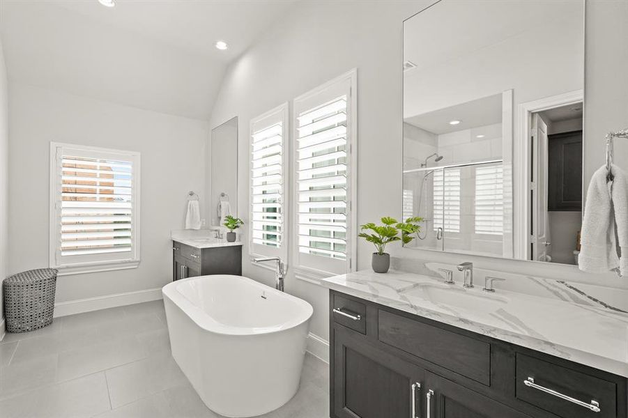 Relax after a long day in this wonderful Primary Bathroom with garden tub, separate sinks with its very own mirror, quartz countertops, plantation shutters, and tile floors.