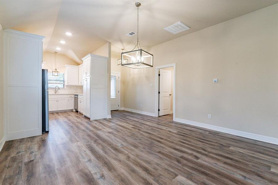 Open concept with decorative lighting, vaulted ceilings and gorgeous white cabinetry and trim