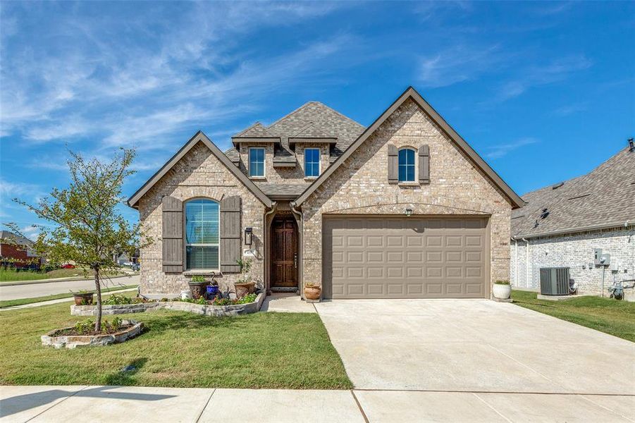 French country home with a garage, central air condition unit, and a front yard