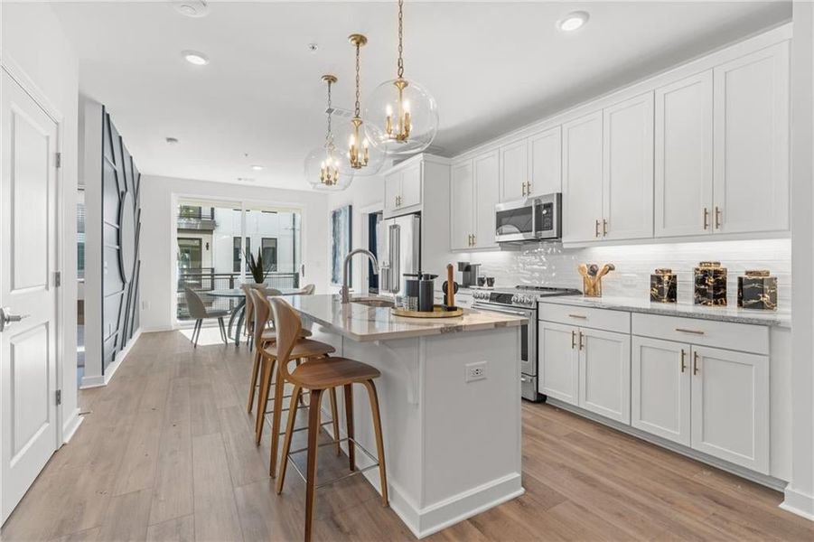 Kitchen with white cabinets, a center island with sink, and stainless steel appliances. *Not actual home-Representative purposes only*