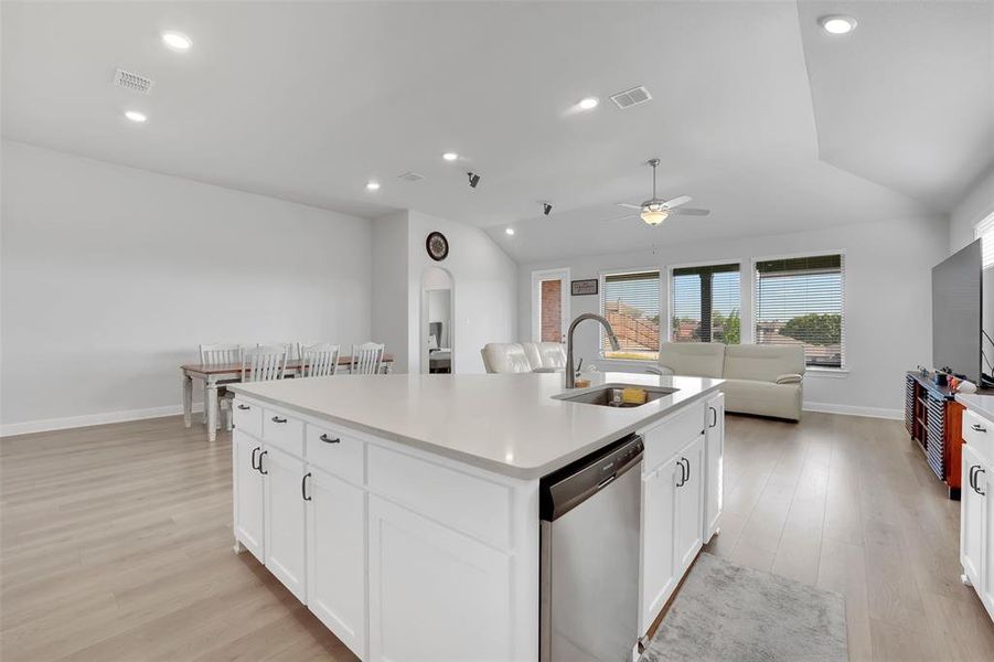 Kitchen featuring an island with sink, white cabinets, dishwasher, and sink