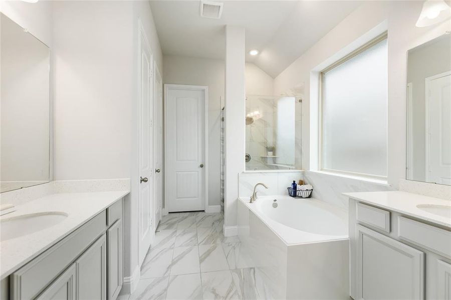 The spa-like Primary Bathroom features separate sinks, soaking tub, walk-in shower, and walk-in closet