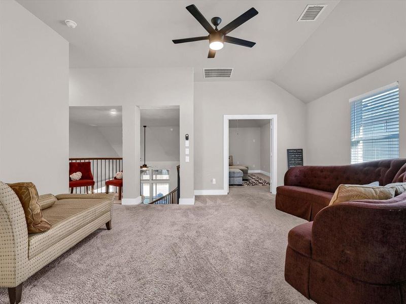 Carpeted living room with lofted ceiling and ceiling fan