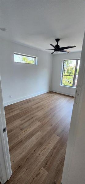 Spare room featuring wood-type flooring, ceiling fan, and plenty of natural light