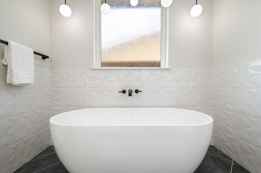 Bathroom with tile walls, tile patterned floors, and a washtub