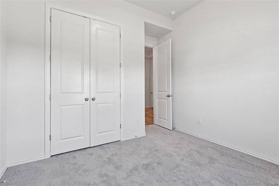 Unfurnished bedroom featuring light carpet and a closet