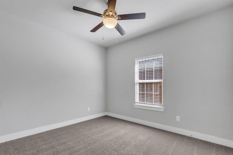 Carpeted spare room featuring ceiling fan