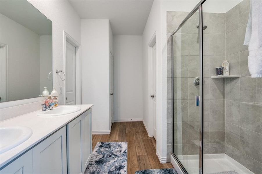 Bathroom featuring wood-type flooring, vanity, and an enclosed shower