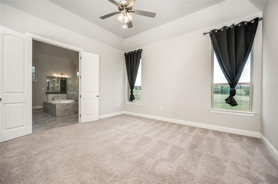 Unfurnished bedroom with ceiling fan, connected bathroom, and carpet flooring