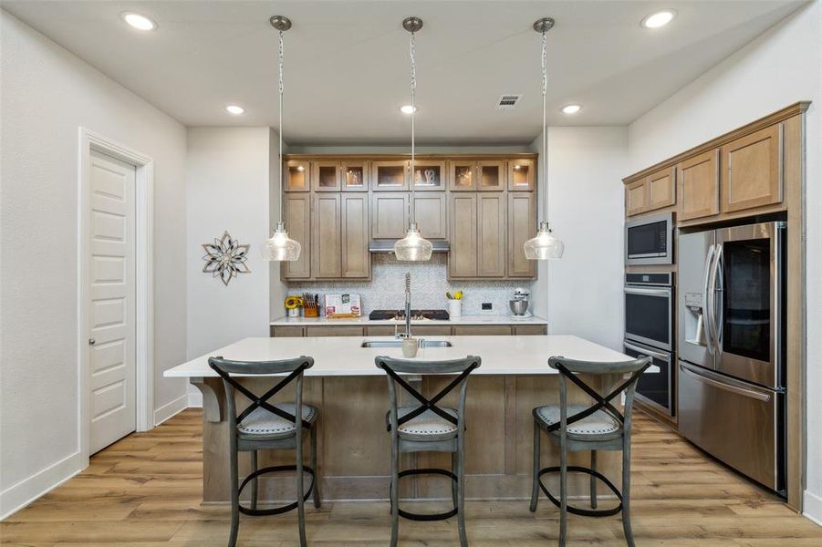 Kitchen has extended glass front lighted upper cabinets.  The door to the walk in pantry is on the left.