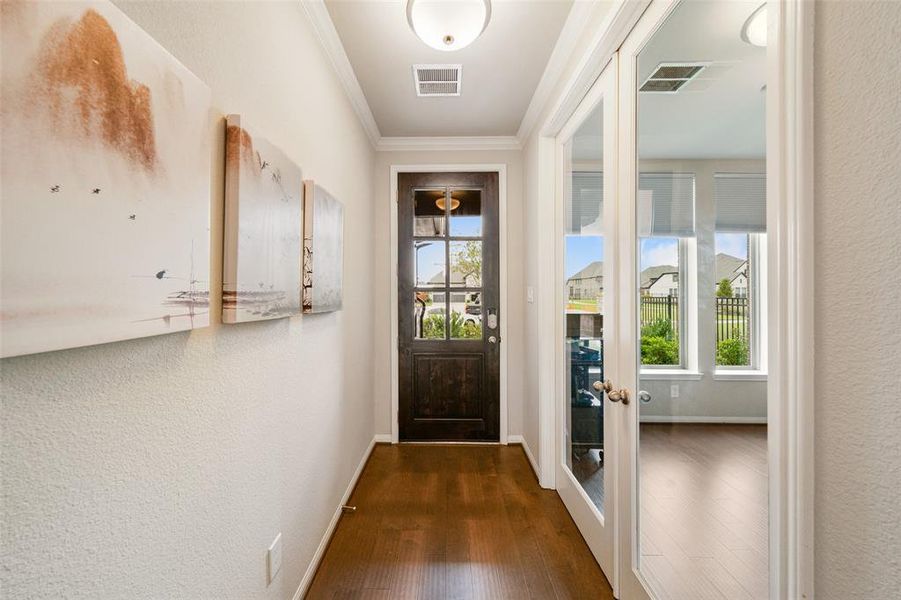 Such a light & bright inviting entrance hallway featuring hardwood floors, a neutral color palette, and modern artwork. The space includes a glass-panel door that leads to a brightly lit room, providing a seamless transition to the rest of the home.