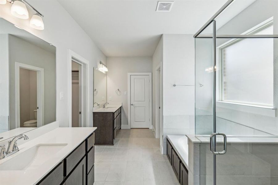 Full bathroom featuring tile patterned flooring, toilet, shower with separate bathtub, and vanity