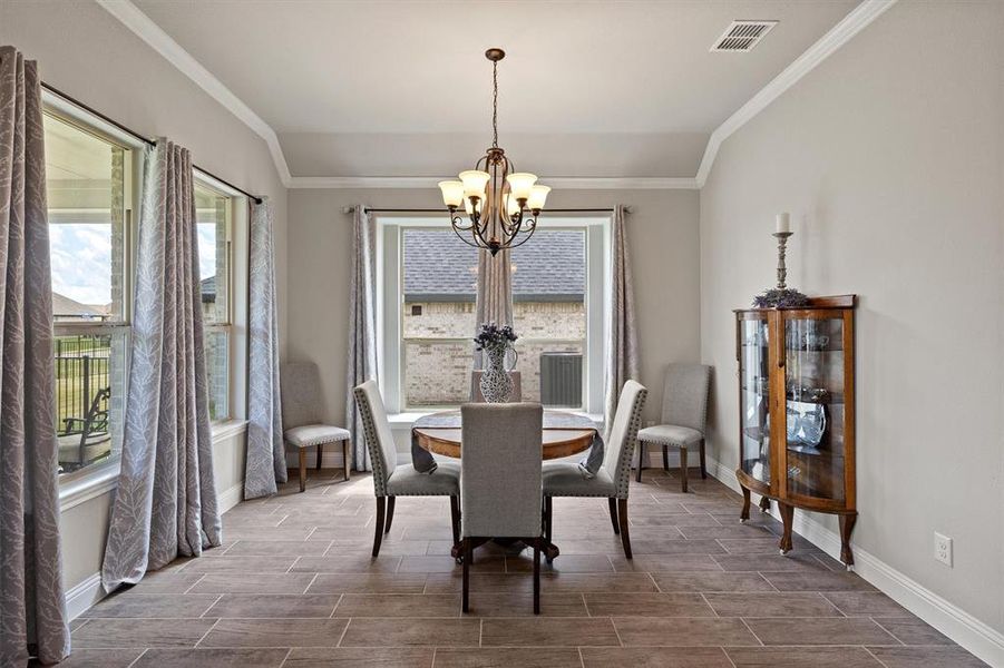 Dining space featuring lofted ceiling, a chandelier, and ornamental molding