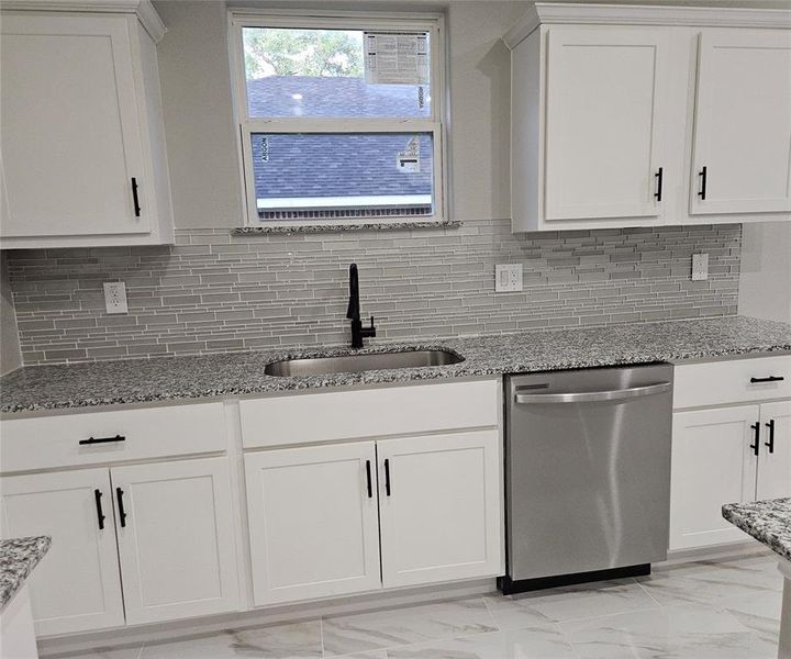 Kitchen featuring light stone countertops, dishwasher, sink, decorative backsplash, and white cabinetry