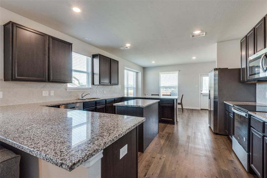 Kitchen featuring stainless steel appliances, a wealth of natural light, a center island, and light wood-type flooring